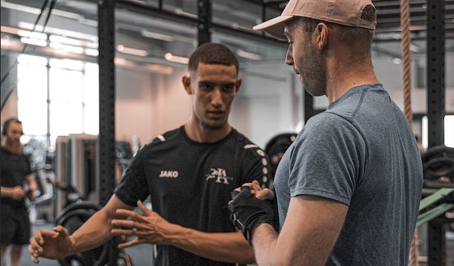 Personal trainer geeft uitleg tijdens een sessie